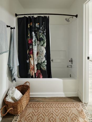 A bathroom with a shower curtain and a basket of towels.